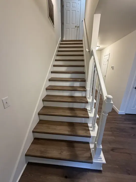 Staircase with white risers and handrail between warm white walls, Chattanooga, TN