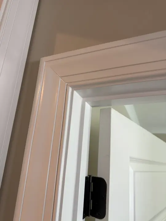 Close-up of fluted white door casing with smooth enamel finish against beige wall in Chattanooga, TN