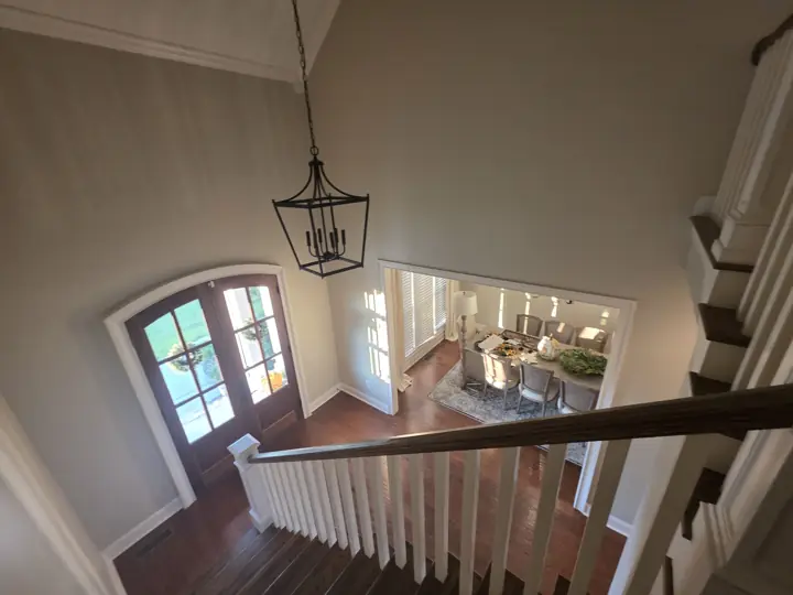 Two-story foyer in soft greige with white balusters and arched entry doors after interior painting in Cleveland, TN