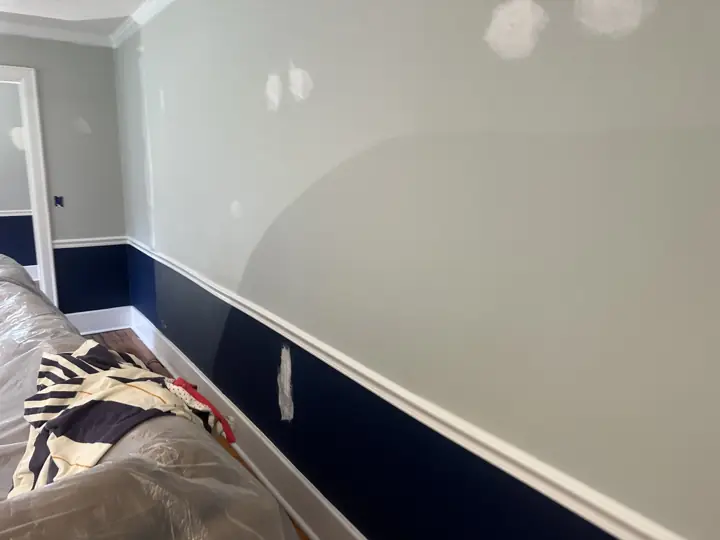 Patched walls above navy wainscoting and white chair rail before painting in Ringgold, GA