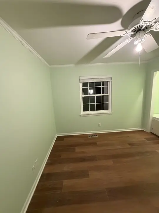 Small mint green bedroom with white window casing in Chattanooga, TN