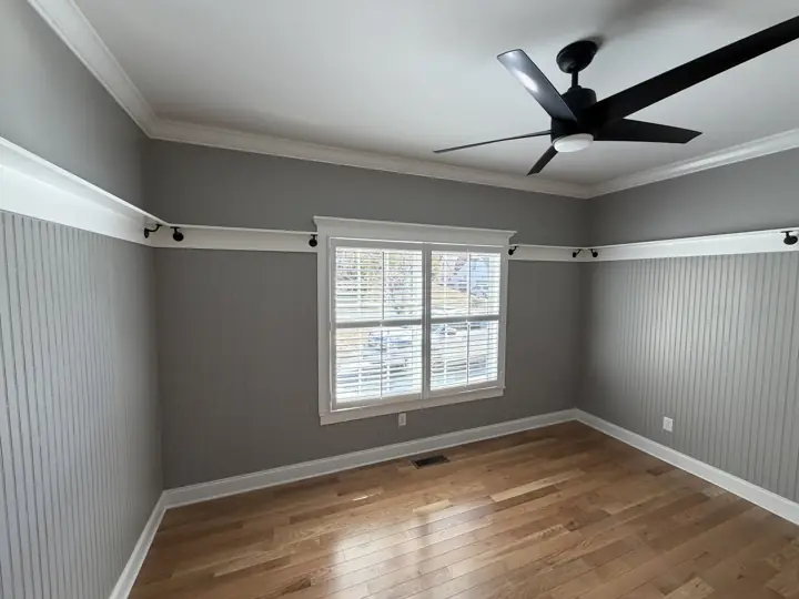 Bedroom with gray beadboard walls, white shelf rail and crown molding in Harrison, TN