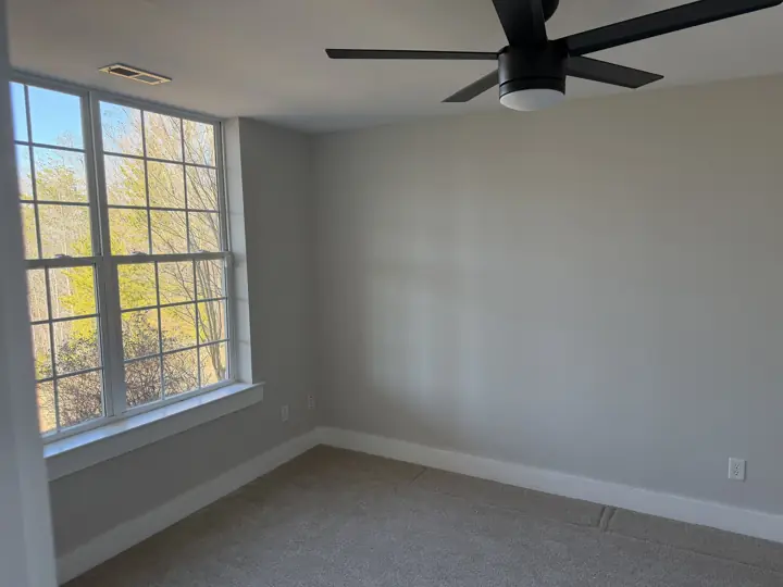 Light gray bedroom with white baseboards and window sill after interior painting in Harrison, TN
