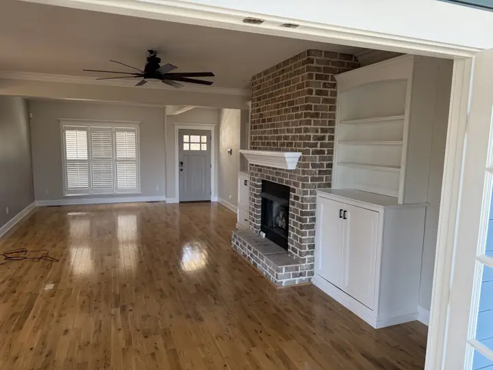 Living room with greige walls, white built-in shelving and crown molding beside a brick fireplace in Harrison, TN