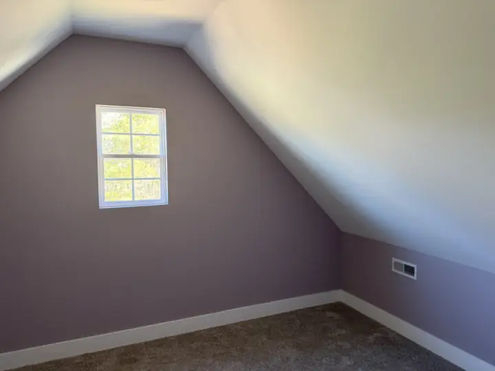 Attic bedroom with soft mauve walls under a sloped white ceiling in Harrison, TN