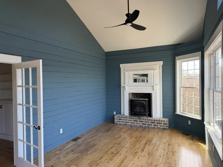 Navy shiplap walls, vaulted white ceiling and white fireplace surround in a sunroom in Harrison, TN