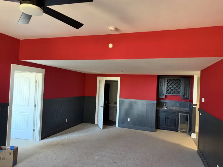 Game room with red walls above charcoal beadboard wainscoting after interior painting in Harrison, TN