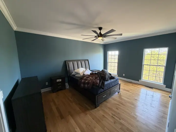 Primary bedroom with slate blue walls and white crown molding after interior painting in Harrison, TN