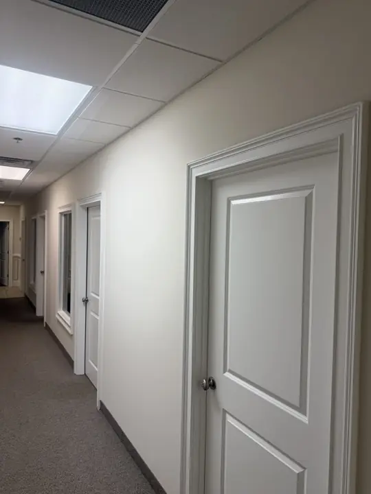 Office corridor with white raised-panel doors and wide casings after painting in Cleveland, TN