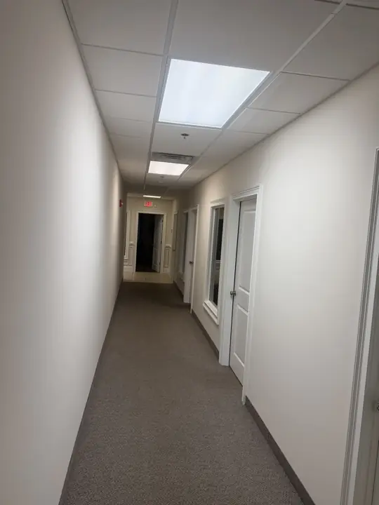 Long carpeted office corridor with cream walls and white door trim in Cleveland, TN