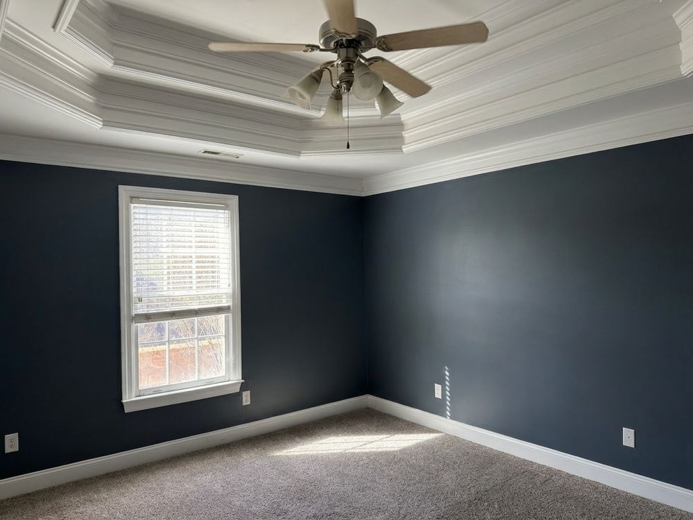 Bedroom with deep navy walls and a tray ceiling