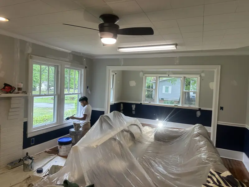 Painter working in a living room with furniture wrapped in plastic in Ringgold, GA