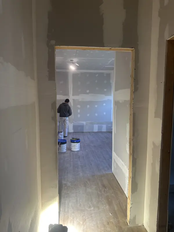 Crew member prepping a hallway and room for paint