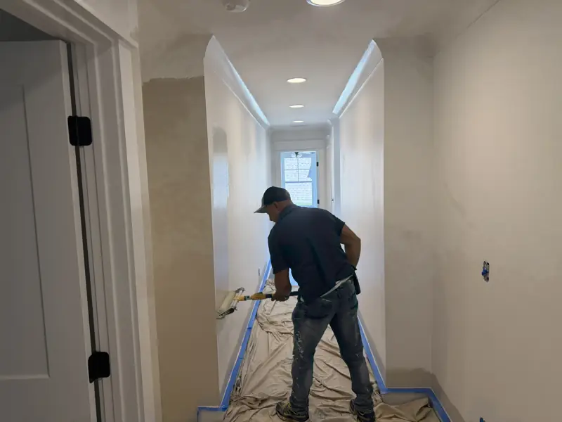 Painter rolling a hallway wall with taped baseboards in Soddy-Daisy, TN