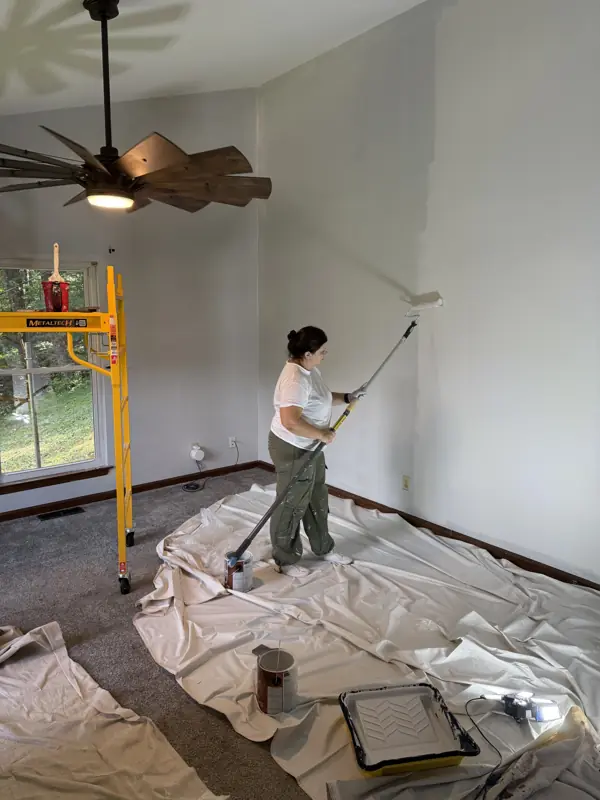 Painter rolling a vaulted wall with an extension pole, floors covered with drop cloths in Chattanooga, TN