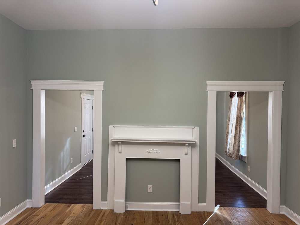 Living room with sage green walls and hardwood floors