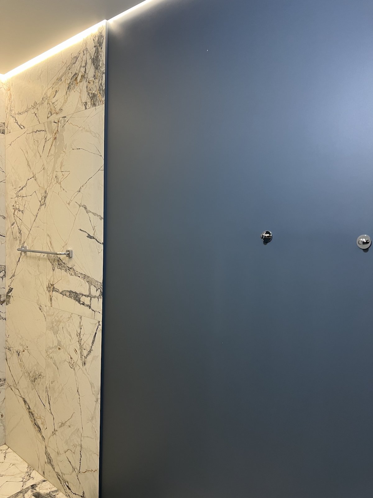 Premium bathroom with marble walls and deep blue accent panel