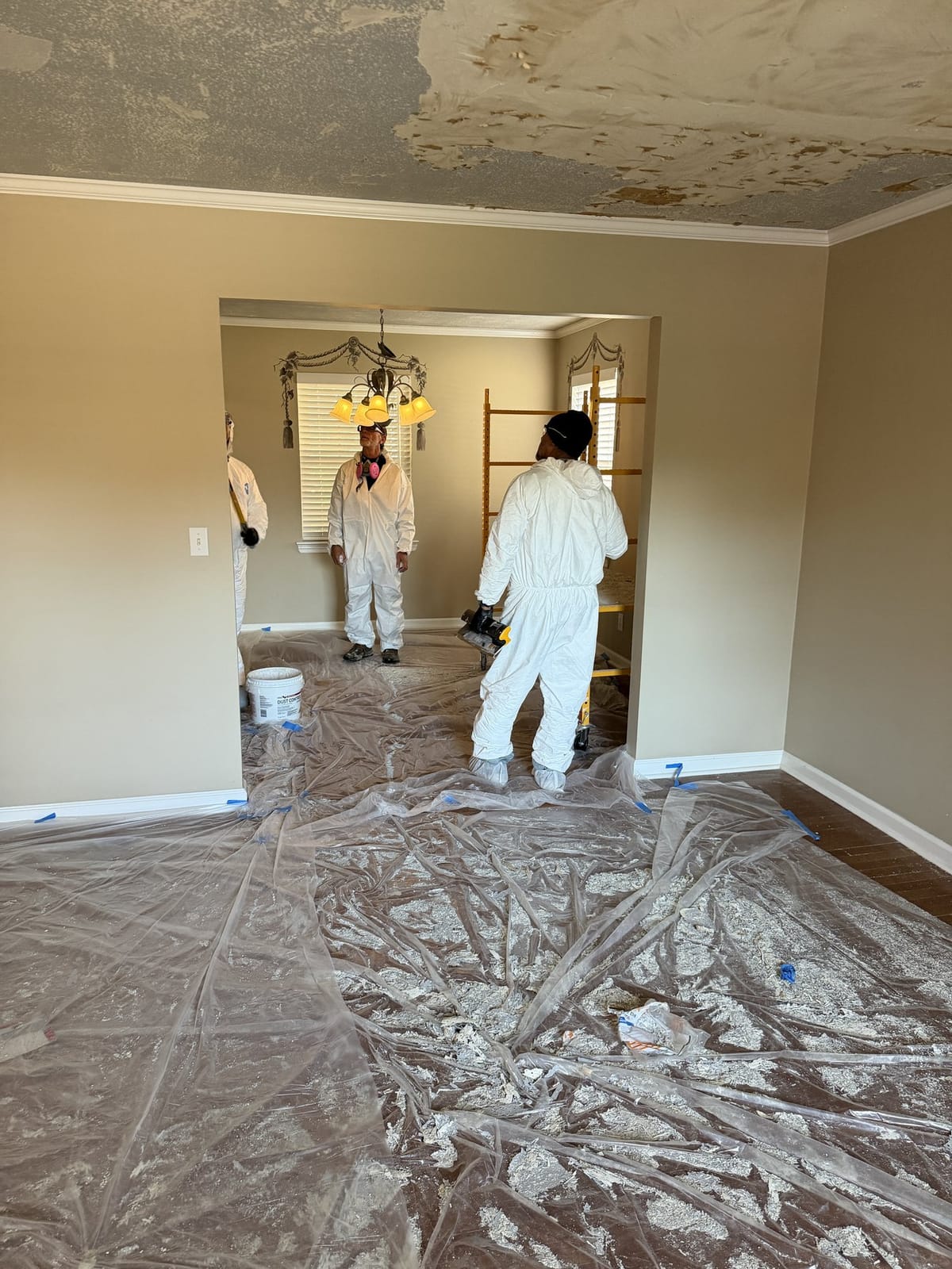 Crew in full PPE prepping a ceiling for paint